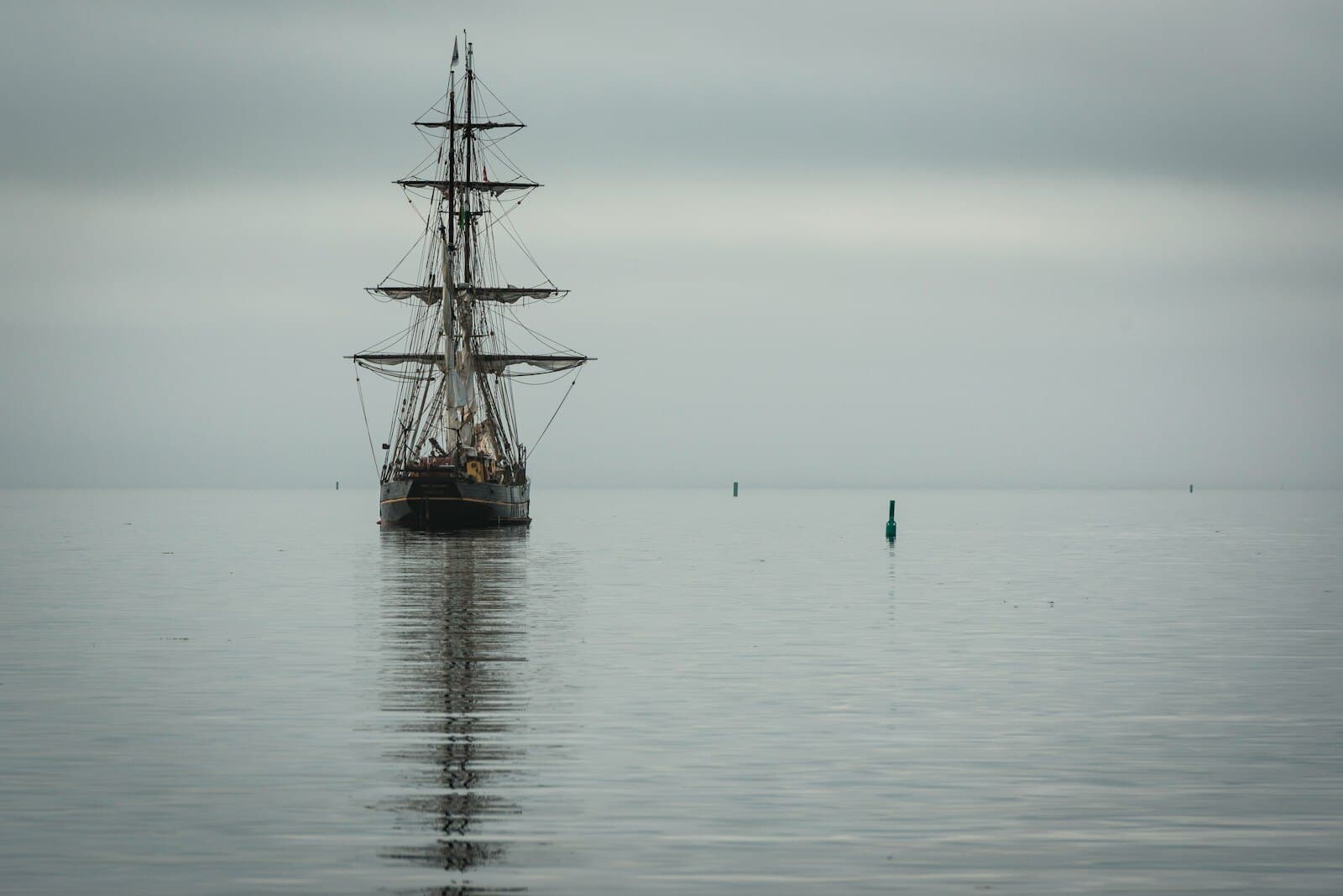 A lone wooden tall ship on calm grey water