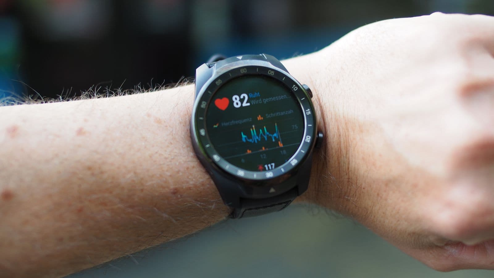 A smartwatch on a wrist showing a live heart-rate reading and trend graph, the everyday example of continuous monitoring