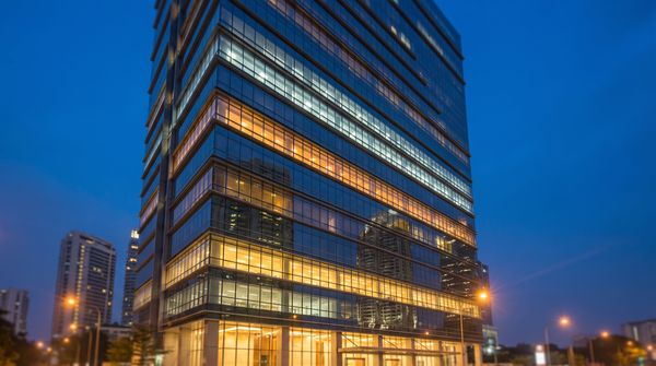Malaysian office tower glass facade at dusk with tiered bands of lit windows suggesting an energy rating scale