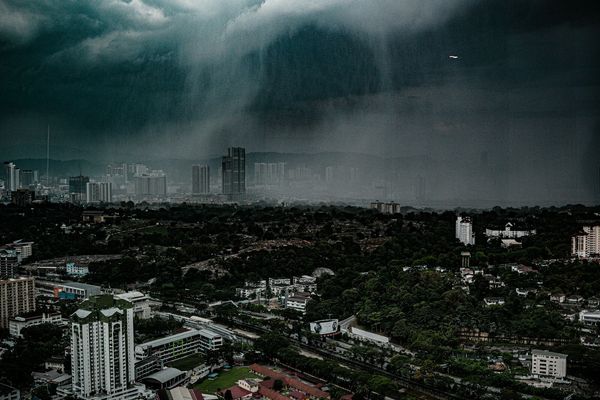 A tropical rainstorm sweeping over a humid city skyline