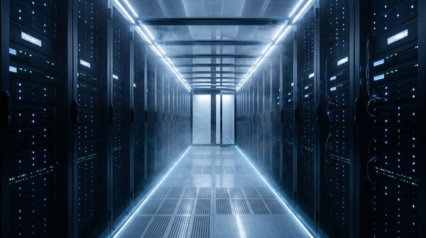Data centre cold aisle with rows of server racks glowing with blue LED lights, perforated floor tiles and a haze of chilled air, containment door ajar at the far end